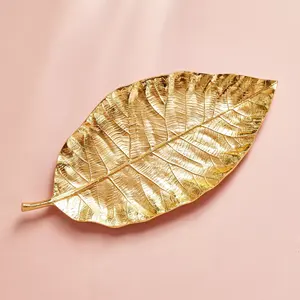 Plato de hojas decorativas de metal similar a las hojas de Magnolia macrophylla y Terminalia El plato es de color dorado - Product Image 1