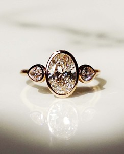 Bague à trois pierres sertie de moissanite ovale de 7x9 mm avec pierres latérales en forme de poire, plaquée or rose - Product Image 1