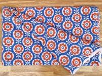 T-shirt pour enfants avec motifs floraux orange et blanc sur fond bleu, créant un design joyeux et ludique, parfait pour tous les jours.