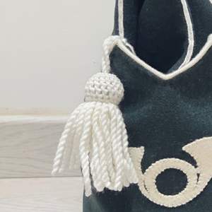 Ceci est un chapeau bicorne en feutre de laine vert foncé avec une bordure blanche et un pompon décoratif, doté d'un emblème de corne de cheval. - Product Image 2