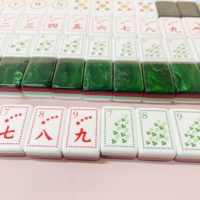 Ensemble de Mahjong de luxe vert émeraude avec dos marbré, côtés rayés et tuiles de jeu de Mahjong gravées avec des motifs botaniques