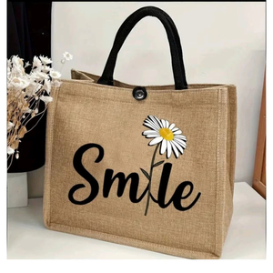 Sac fourre-tout en jute Smile Daisy avec impression graphique et typographique de marguerites en jute naturelle et noire, conçu pour le transport écologique quotidien - Product Image 1