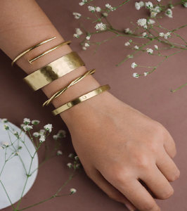 Conjunto de pulseras doradas, incluyendo un brazalete martillado. Joyas apilables, modernas y minimalistas. Disponible a precios mayoristas. - Product Image 1