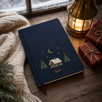 Journal de Noël personnalisé LABON, couverture rigide en lin bleu marine, broderie cabane enneigée, lune, étoiles, traîneau, pages lignées, ruban