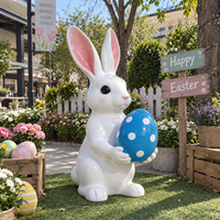 Sculpture de lapin de dessin animé tenant un œuf tacheté avec de longues oreilles et une forme d'animal ludique pour la décoration extérieure sur le thème de Pâques