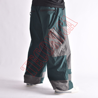 Pantalon de neige vert et gris hiver 2025, style bicolore, taille à cordon de serrage, poches zippées de rangement et système de ventilation