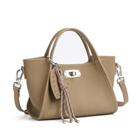 Sac à main beige pour femme, forme trapèze, avec anse supérieure, bandoulière, fermoir rotatif, pompon, texture grainée, accessoires argentés, taille moyenne