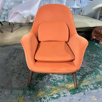 Fauteuil de salon rétro en tissu orange, confortable et rembourré, idéal pour la lecture dans une chambre ou un appartement