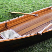 Canoë gonflable artisanal en fibre de verre et bois avec finition teintée foncée, durable et résistant à l'eau, pour 4 pagaillards, adapté aux lacs et rivières.