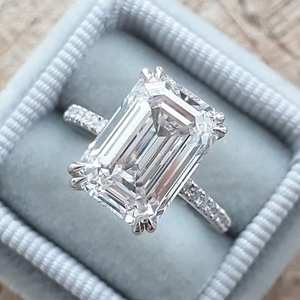 Anillo de compromiso de moissanita de corte esmeralda de lujo de 6 quilates en oro blanco con doble halo invisible de cuatro puntas y banda de media eternidad - Product Image 1