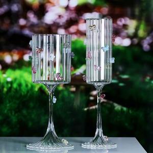 La transparencia de una copa de vino de cristal con un detalle de mariposa crea un contraste visualmente atractivo contra los vinos de colores intensos. - Product Image 6