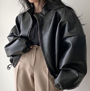 Trendy black oversized leather bomber jacket with slouchy sleeves, styled with high-waisted beige pants, at wholesale prices. - Product Image 1