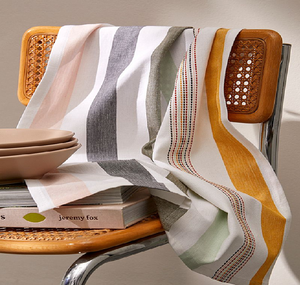 Modern multi-colored striped cotton towel draped on a woven wooden chair. Available at wholesale prices. - Product Image 1
