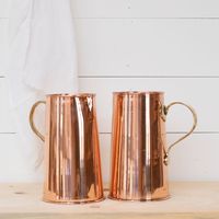 Jugs en cuivre poli élégants offrant une surface brillante, idéales pour les thèmes de décoration intérieure modernes.
