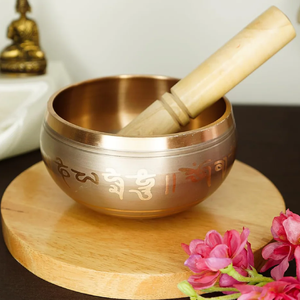 Cuenco de canto tibetano dorado con mantra escrito en su superficie y palo de madera para producir sonido disponible a precios al por mayor - Product Image 1