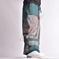 Pantalon de neige vert et gris hiver 2025, style bicolore, taille à cordon de serrage, poches zippées de rangement et système de ventilation