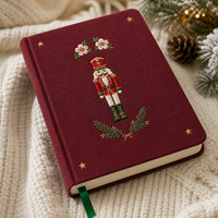 Diario personalizado LABON de Navidad con diseño de Cascanueces, tapa dura color burdeos, estrella dorada bordada, flor rosa y páginas rayadas con motivos de árbol de Navidad.