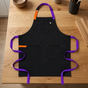 Tablier en toile robuste et réutilisable noir avec bretelles violettes, accents orange et trois poches pour la cuisine - Product Image 1