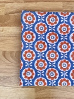 T-shirt pour enfants avec motifs floraux orange et blanc sur fond bleu, créant un design joyeux et ludique, parfait pour tous les jours.