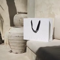 Sac de shopping en papier gaufré de luxe personnalisé avec poignées en corde pour l'emballage de vêtements et de cadeaux de marques de détail