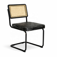 Chaise de salle à manger industrielle moderne en cuir de buffle, dossier en rotin, structure en métal noir, non pliable |   Conception en cantilever fabriquée en Inde AKKU