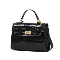 Sac à main noir pour femme, forme trapézoïdale structurée, poignée supérieure, fermoir rotatif, bandoulière, quincaillerie dorée, motif crocodile brillant