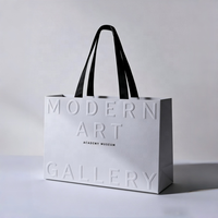 Sac de shopping en papier gaufré de luxe personnalisé avec poignées en corde pour l'emballage de vêtements et de cadeaux de marques de détail