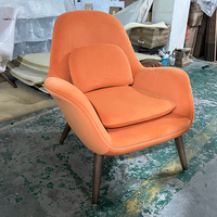 Fauteuil de salon rétro en tissu orange, confortable et rembourré, idéal pour la lecture dans une chambre ou un appartement