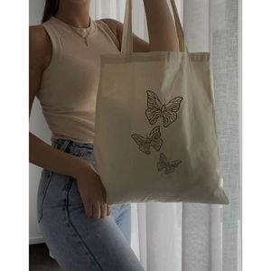 Sac fourre-tout en toile de coton avec motif de papillon minimaliste en ligne, en beige, avec un design aux contours net, conçu pour le transport quotidien à l'épaule - Product Image 1