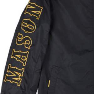 Chaqueta cortavientos Mason negra unisex de poliéster con logotipo bordado en la parte delantera y trasera, chaqueta de ropa universitaria ligera resistente al agua - Product Image 5
