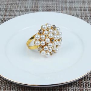 Des anneaux de serviette en métal et des perles blanches présentent des motifs complexes et magnifiques qui ajoutent du caractère et du charme à la table. - Product Image 2