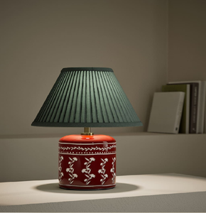 Une base de lampe de table en céramique rouge ornée de délicats motifs floraux blancs, avec un élégant abat-jour vert plissé - Product Image 1