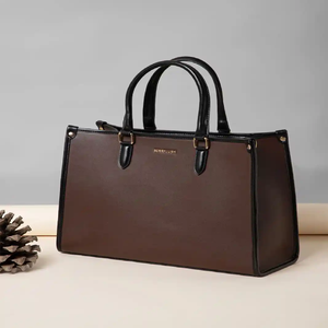 A structured brown <b>tote</b> with <b>black</b> trim next to a marble coaster is now available at wholesale prices. - Product Image 1