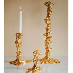 El portavelas de metal dorado se erige como una fusión atemporal de arte y utilidad, acunando suaves llamas en su abrazo esculpido - Product Image 6