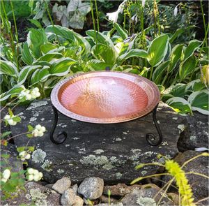 Baño decorativo para pájaros con lavabo de cobre martillado con superficie brillante y reflectante, soportado por un soporte de metal negro con patas curvas - Product Image 1