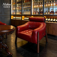 Fauteuil d'appoint moderne de luxe en cuir rouge, design capitonné avec appui-tête cylindrique et détails à boucles, pour salon, club ou bar