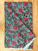 Kain katun murni premium dengan motif bunga berwarna merah muda cerah, pola bunga merambat yang indah dicetak di atas kain berwarna biru kehijauan lembut.