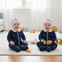 Pyjama bébé tricoté sur mesure bleu marine avec chaussons intégrés, fermeture à boutons-pression et bonnet brodé bateau à voile unique
