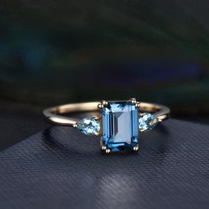 แหวนทองคำประดับบลูโทแพซทรงเอเมอรัลด์คัทและโทแพซทรงหยดน้ำ 3 เม็ด แหวนแต่งงานแบบ 8 กรงเล็บ แหวนประจำเดือนธันวาคม ผลิตเครื่องประดับโดยผู้ผลิตในอินเดีย - Product Image 3