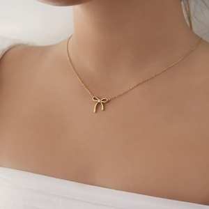 Encantador collar minimalista con forma de lazo dorado, disponible a precios de mayoreo. - Product Image 1