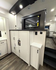 Caravane de voyage moderne avec cuisine coulissante, armoires blanches, plan de travail noir, sol en bois, capacité 6 personnes - Product Image 4