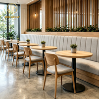 Ensemble de mobilier commercial moderne pour café et restaurant, comprenant une banquette rembourrée Ron Group, une table ronde en bois et des chaises rembourrées en tissu.