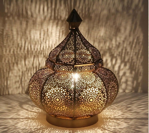 Una lámpara de mesa bellamente elaborada con metalistería detallada y una forma de cúpula que proyecta intrincados patrones de luz en toda la superficie - Product Image 1