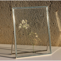 Cadre photo flottant carré en métal noir de dernière génération avec verre sur les côtés pour une présentation géométrique moderne sur table