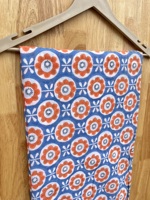 T-shirt pour enfants avec motifs floraux orange et blanc sur fond bleu, créant un design joyeux et ludique, parfait pour tous les jours.