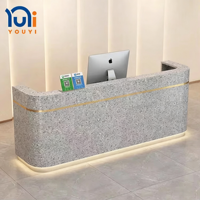 Comptoir d'accueil minimaliste en marbre courbé avec éclairage LED inférieur et finition dorée pour bureau, hôtel, spa, hall d'entrée