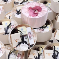 Élégante boîte à dragées cylindrique rose poudré en satin avec accent de fausse fleur et d'orchidée, emballage de luxe pour cadeaux de mariage pour invités