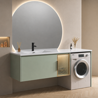 Meuble-lavabo moderne vert sauge avec lavabo, miroir LED rond mural, armoire de buanderie et espace pour machine à laver, idéal pour projets hôteliers