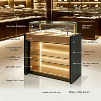 Vitrine à bijoux moderne et élégante avec dessus en bois clair, panneau latéral foncé, armoire en verre transparent avec éclairage LED chaud intégré pour la vente au détail de bijoux