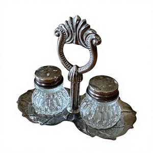 Ensemble élégant de salière et poivrière en métal avec base en forme de feuille et poignée ornée pour une utilisation sur table - Product Image 1